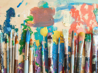 Close-up of different paintbrushes in paints lying on the painting
